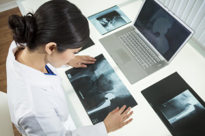 Female Woman Hospital Doctor Looking at  X-Rays & Laptop